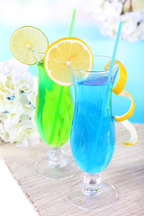 Glasses of cocktails on table on light blue background