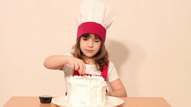 little girl cook decorates a cake