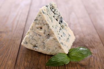Tasty blue cheese with basil, on wooden table