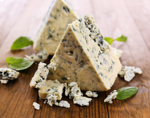 Tasty blue cheese with basil, on wooden table