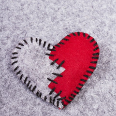 stitched broken felt heart on a on a gray background