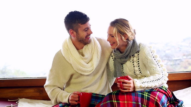 Cute couple relaxing under a blanket in their winter cabin