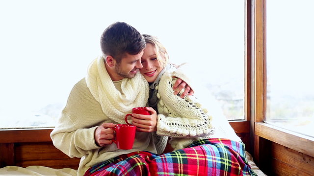 Cute Couple Relaxing Under A Blanket In Their Ski Lodge