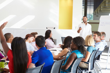 Businessman Addressing Meeting Around Boardroom Table