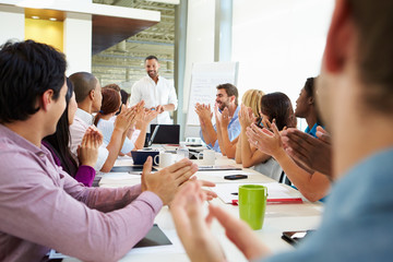 Businessman Addressing Meeting Around Boardroom Table