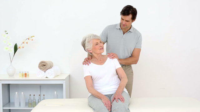 Physiotherapist smiling at camera with senior patient
