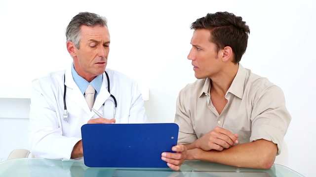 Patient listening to his doctor holding clipboard