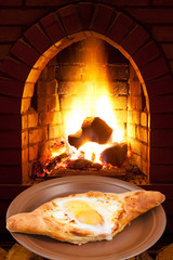 adzharian khachapuri with egg and fire in stove