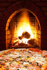 pizza with ham, mushroom and open fire in stove