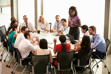 Obraz premium Businesswoman Addressing Meeting Around Boardroom Table