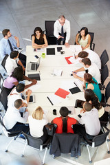 Businessman Addressing Meeting Around Boardroom Table