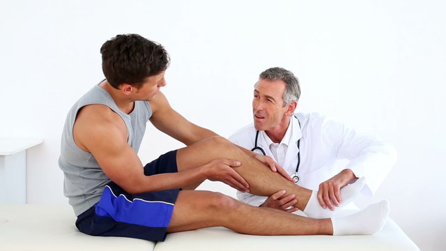 Mature doctor touching sportsmans injured ankle