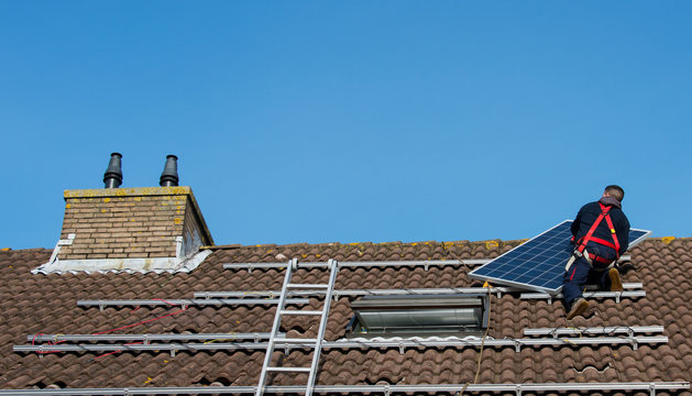 Man Putting The Solar Panel On The Roof