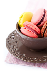 Colorful macaroons in brown cup on white background