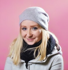 Young woman in warm clothes on a pink background.