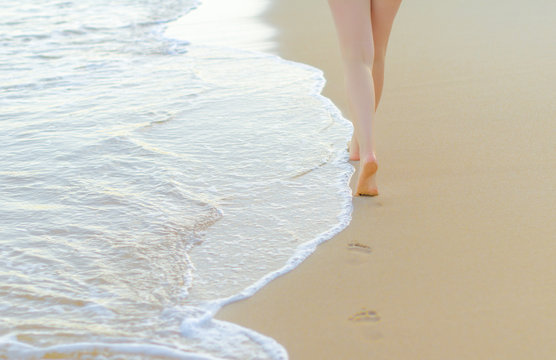 Pair Of Female Legs On A Seashore.