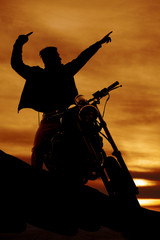 silhouette of a man on a motorcycle pointing