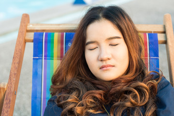 Close-up of asian woman relaxing on beach chair