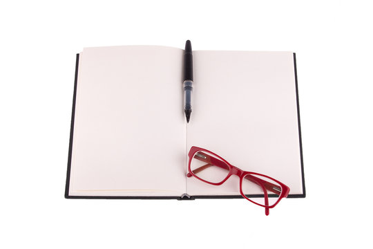 Red glasses and a fountain pen placed on notebook.