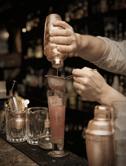 Bartender is straining cocktail