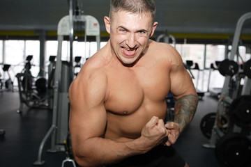 Naklejka premium Bodybuilder training in the gym at full power