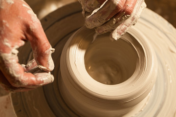 Hands working on pottery wheel , close up