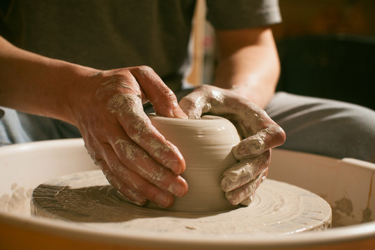 Hands working on pottery wheel , close up retro style toned