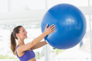 Fototapeta premium Smiling fit young woman holding fitness ball