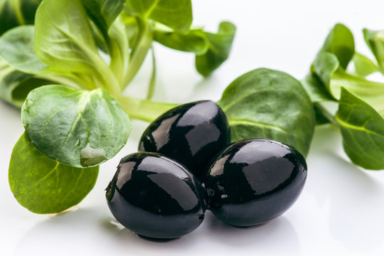 Black olives and salad leaves isolated on white