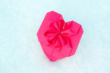 One heart shape from pink paper in the snow for Valentines day