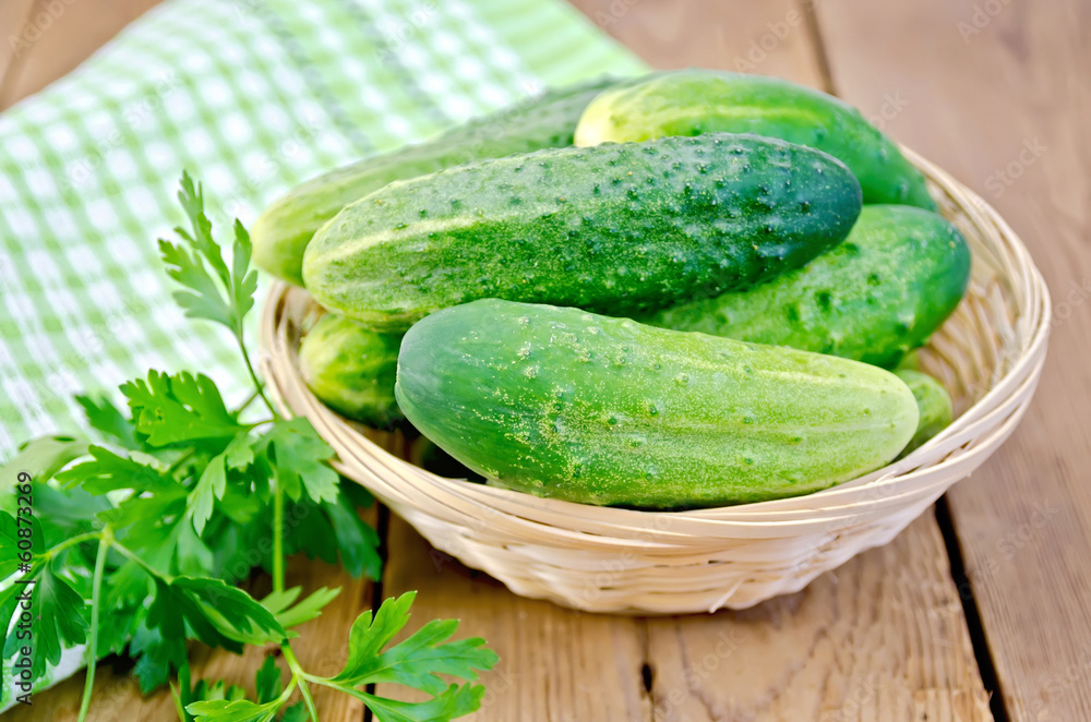 Wall mural cucumbers with parsley in wicker basket on a board