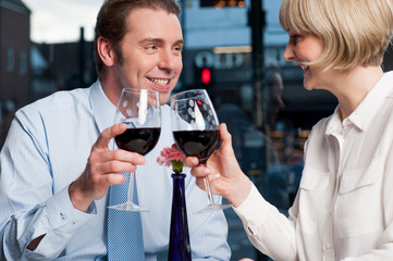 Happy couple raises a glass of red wine