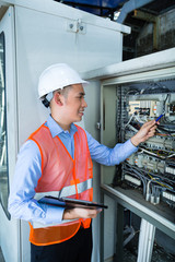 Asian Electrician at panel on construction site