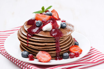 pancakes with cream and berries on a white wooden table