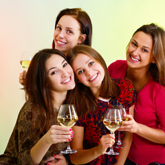 Happy young women friends touching the glasses with each other o