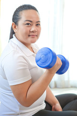 Fat woman does fitness with dumbbell