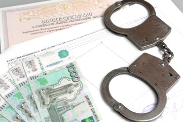 Handcuffs and money against the background of the certificate of