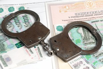 Handcuffs and money against the background of the certificate of