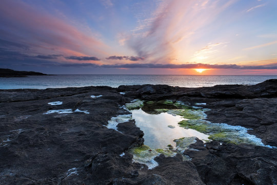 Sunset over a tidal pool . Rocky coast of Scotland .
