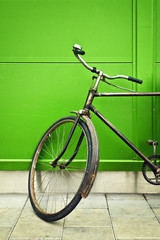 Naklejka na ściany i meble Old bicycle leaning on green wall