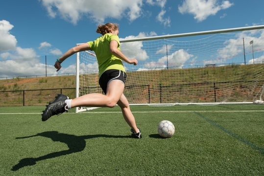 Female soccer player shooting on goal wide low angle