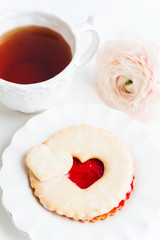 A cookie with strawberry jam and cup of tea