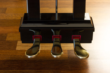 Grand piano pedals over a wooden floor