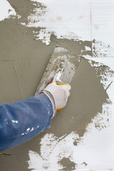 Worker spreading  mortar over styrofoam insulation with trowel