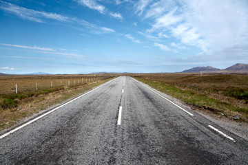 Fototapeta na wymiar Desert road running through Isle of North Uist, Outer Hebrides