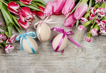 Bouquet of pink tulips and easter eggs on wooden background