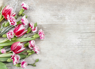 Bouquet of pink tulips and red carnations on wooden background.