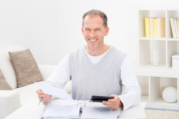 Happy Mature Man Holding Calculator And Bills