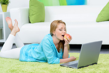 Fototapeta premium woman relaxing with an apple in front of her laptop.