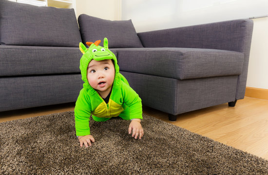 Baby creeping at home with dinosaur dressing